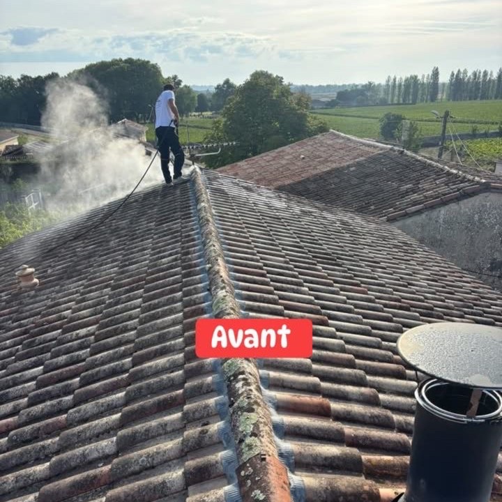 Artisan couvreur nettoyant à la vapeur une toiture couverte de mousses avant traitement